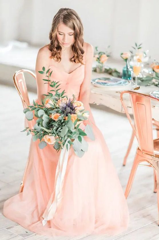 a gorgeous spaghetti strap peachy wedding dress with drapings and a peachy wedding bouquet