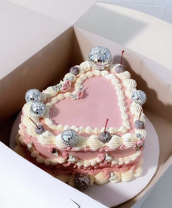 a jaw-dropping pink lambeth heart-shaped wedding cake with silver cherries and disco balls on top is amazing