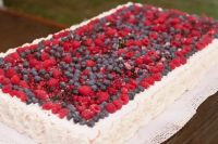a large sheet wedding cake topped with fresh berries is a cool idea for a casual or just more relaxed summer wedding