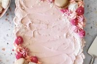 a lovely small pink frosting sheet wedding cake topped with pink and white meringues and macarons is amazing
