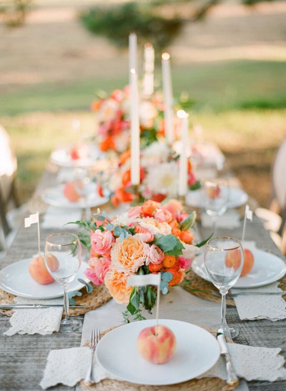 a lovely summer wedding tablescape with pink, peachy and coral blooms, peaches on each place setting and candles