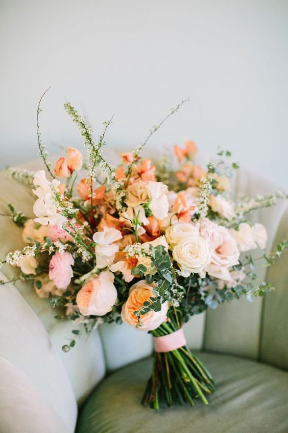 a lovely wedding bouquet of blush, white and peachy blooms, greenery and twigs is amazing for a wedding