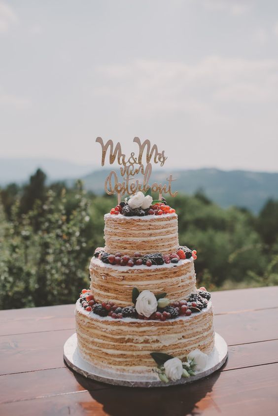 a millefoglie wedding cake styled as a usual tiered wedding cake, topped with berries, blooms and a calligraphy topper