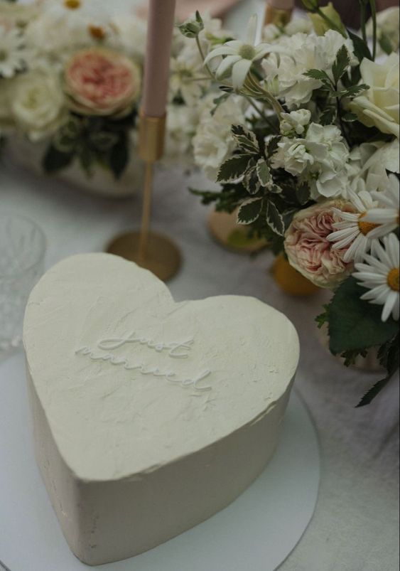 a minimal heart-shaped wedding cake with calligraphy on top is a cool idea for a modern neutral wedding