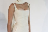 a modern bridal look with a mermaid wedding dress with a corset and straps plus a tulle scarf for more drama in the look