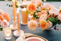 a modern wedding tablescape with a blush and peachy floral centerpiece, mustard and white plates, peachy candles