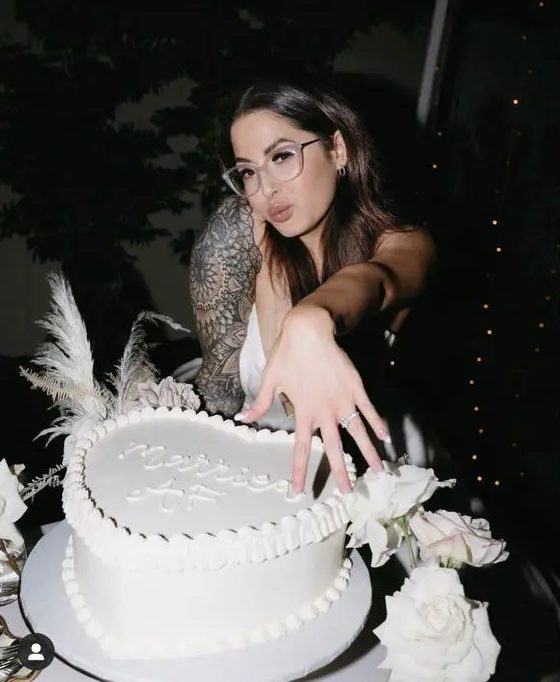a modern white heart-shaped wedding cake with a cool inscription is a fun idea for a modern wedding