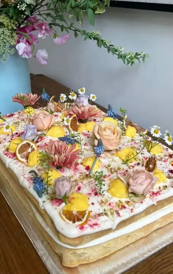 a naked sheet wedding cake topped with fresh blooms in pastel colors and some citrus is amazing for summer