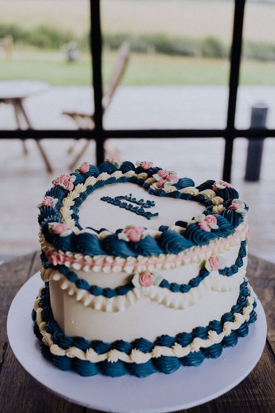 a neutral heart-shaped wedding cake decorated with navy and pink sugar details and with calligraphy on top is a cool vintage-inspired idea