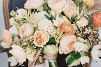 a peachy and creamy wedding bouquet with various blooms, greenery and even pampas grass plus white ribbons