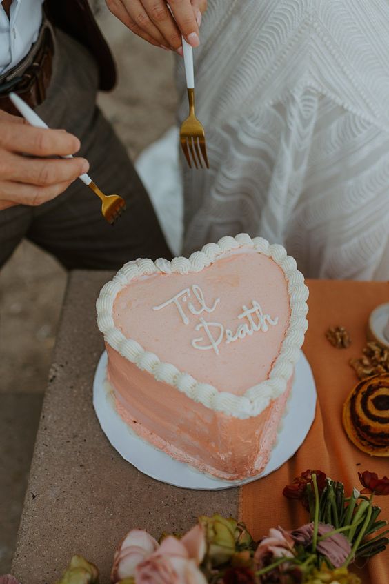 a peachy pink heart-shaped wedding cake with sugar details is a lovely idea for a modern wedding