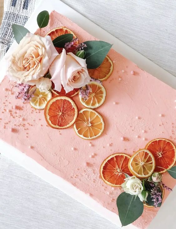 a peachy pink sheet wedding cake with fresh blooms, dried citrus, greenery and pearls is a fantastic idea for a wedding