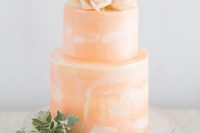 a peachy watercolor wedding cake with a blush bloom on top and some greenery is amazing for spring or summer