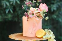 a peachy wedding cake with calligraphy and fresh pink blooms on top is a cool idea for a summer wedding