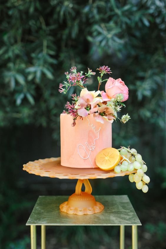 a peachy wedding cake with calligraphy and fresh pink blooms on top is a cool idea for a summer wedding
