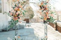a refined wedding arch with blush, orange, peachy and mauve blooms, greenery and white blooming branches is chic