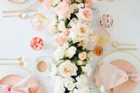 a refined wedding table setting with peachy plates and napkins, white, blush and peachy blooms and greenery plus candies