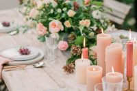 a romantic wedding tablescape with peachy candles and napkins, peachy and orange blooms, greenery and cutlery with peachy handles