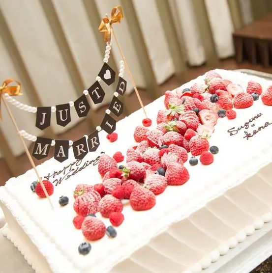 a sheer wedding cake topped with fresh berries and a bunting is a cool idea for a summer wedding