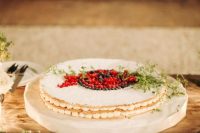 a small round millefoglie topped with some berries and greenery is a stylish idea for a small wedding