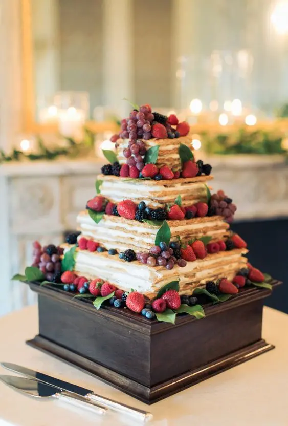 a square tiered millefoglie topped with fresh berries and greenery is a delicious solution for a wedding