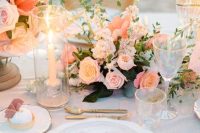 a stunning peachy wedding tablescape with peachy blooms, napkins, gold cutlery and iridescent glasses