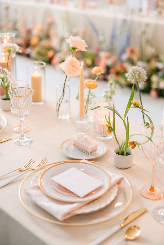 a subtle and delicate wedding tablescape with peachy and blush decor, cluster centerpieces and peachy candles