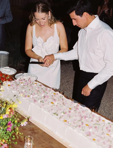 a super long white sheet wedding cake topped with pink blooms and petals is a chic and lovely idea for a spring wedding