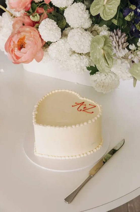 a super simple white heart-shaped wedding cake with monograms is always a good idea for a casual wedding