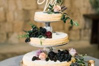 a tiered round millefoglie wedding cake topped with grapes, apples, herbs and some roses plus a monogram is wow