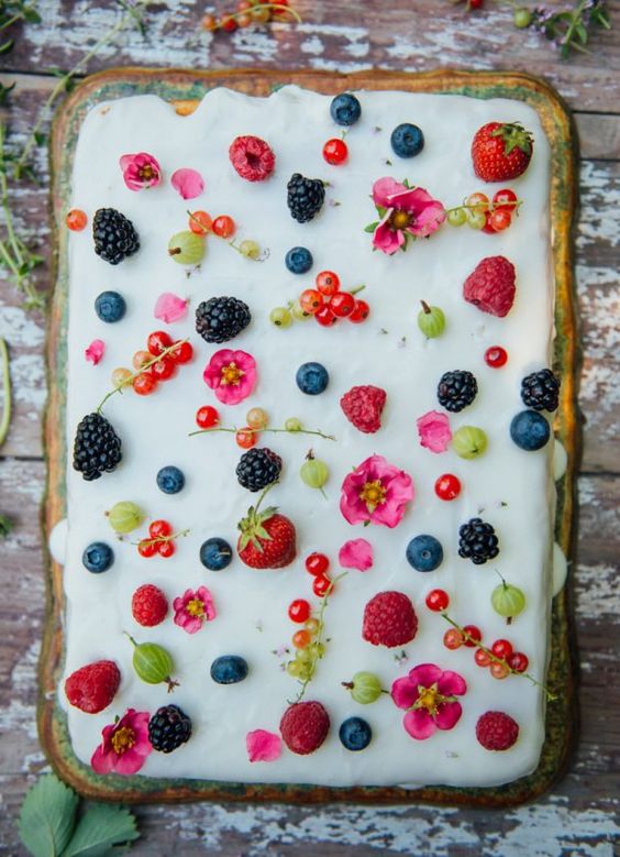 a very simple white sheet wedding cake topped with fresh berries and blooms is a cool idea for a summer wedding