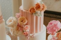 a white and peachy pink wedding cake with blush, peach and pink flowers is a very eye-catchy idea