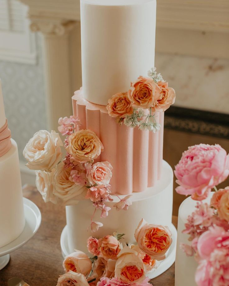 a white and peachy pink wedding cake with blush, peach and pink flowers is a very eye-catchy idea