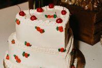 a white heart-shaped wedding cake decorated with small sugar blooms and cherries on top is a cool idea