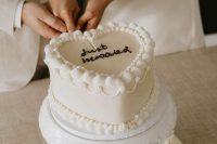 a white heart-shaped wedding cake decorated with sugar details and calligraphy is a perfect modern wedding dessert