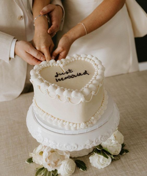 a white heart-shaped wedding cake decorated with sugar details and calligraphy is a perfect modern wedding dessert