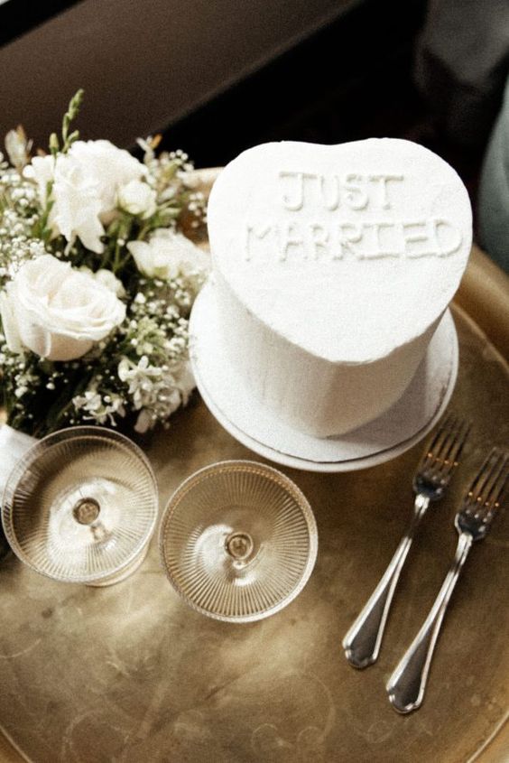 a white heart-shaped wedding cake with some letters on top is a cool idea for a modern wedding