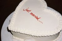a white heart-shaped wedding cake with sugar details and red calligraphy is a cool idea for a modern wedding