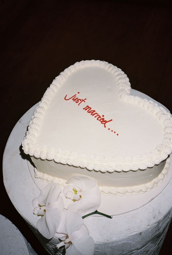 a white heart-shaped wedding cake with sugar details and red calligraphy is a cool idea for a modern wedding