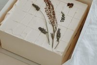 a white sheet wedding cake topped with dried blooms and herbs is a cool idea for a modern boho wedding