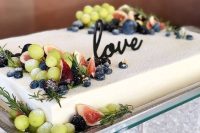 a white sheet wedding cake topped with fresh berries, figs, grapes, herbs and a calligraphy topper is amazing