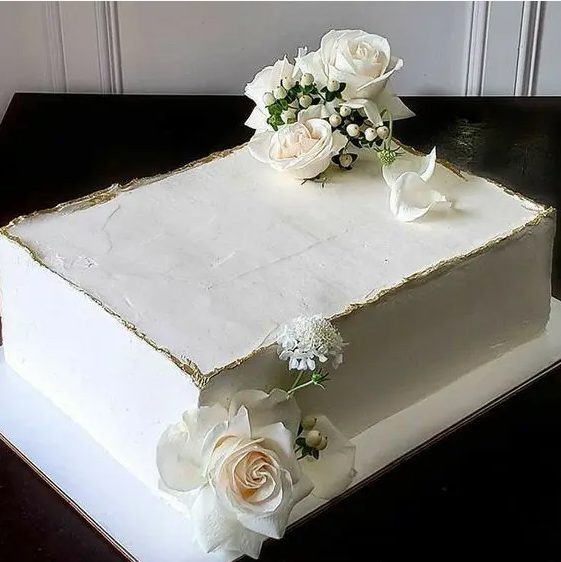 a white sheet wedding cake with a gold edge and fresh white blooms is pure elegance