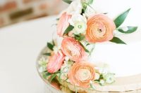 a white wedding cake with peachy pink and orange blooms and white ones plus greenery for a refined wedding