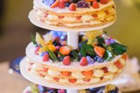 an adorable tiered round millefoglie wedding cake topped with fruit, berries and blooms is amazing