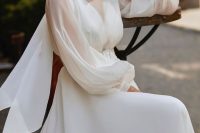 an elegant plain wedding dress with a semi sheer bodice and puff sleeves, a plain skirt and a scarf plus statement earrings