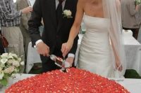 an oversized heart-shaped wedding cake topped with strawberries all over is a beautiful and very romantic idea for a Valenttine wedding