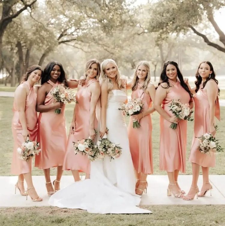 bridesmaid wearing matching Peach Fuzz midi stain dresses with halter necklines and strappy heels