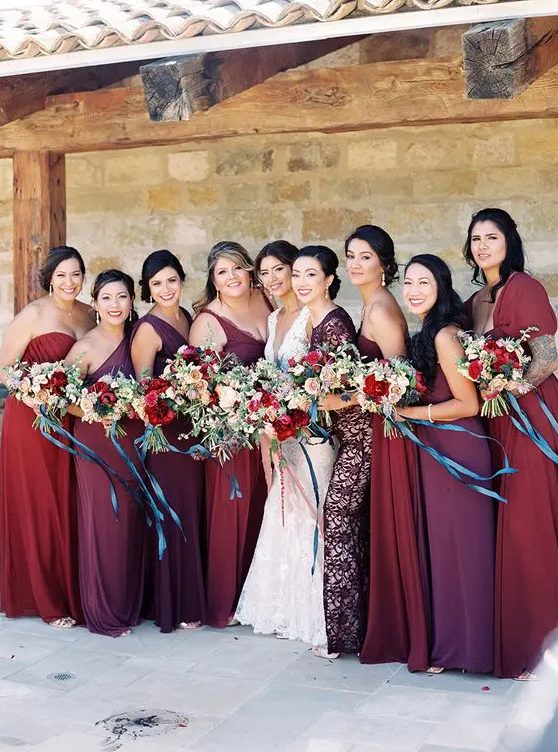 bridesmaids' dresses in the shades of red, purple, burgundy, all different and of different fabrics