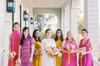 bridesmaids wearing mismatching hot pink, fuchsia, yellow dresses compose a very colorful bridal party