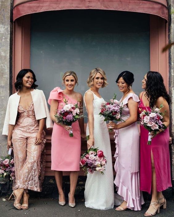 bridesmaids wearing mismatching pink, pale pink and blush maxi, midi dresses and jumpsuits with various detailing